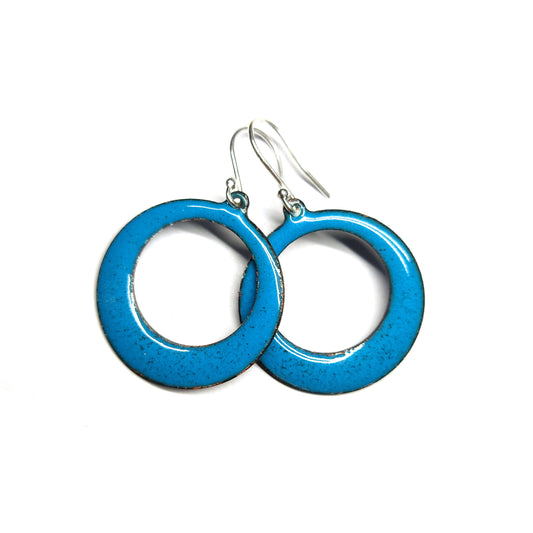 Enamel drop earrings featuring an open circle with teal enamel and a dusting of red enamel. On silver ear hooks.