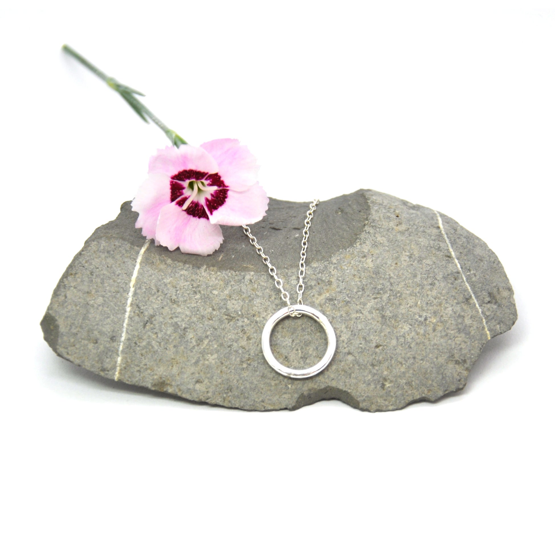 Silver hammered open circle pendant on silver chain - small on pebble with flower