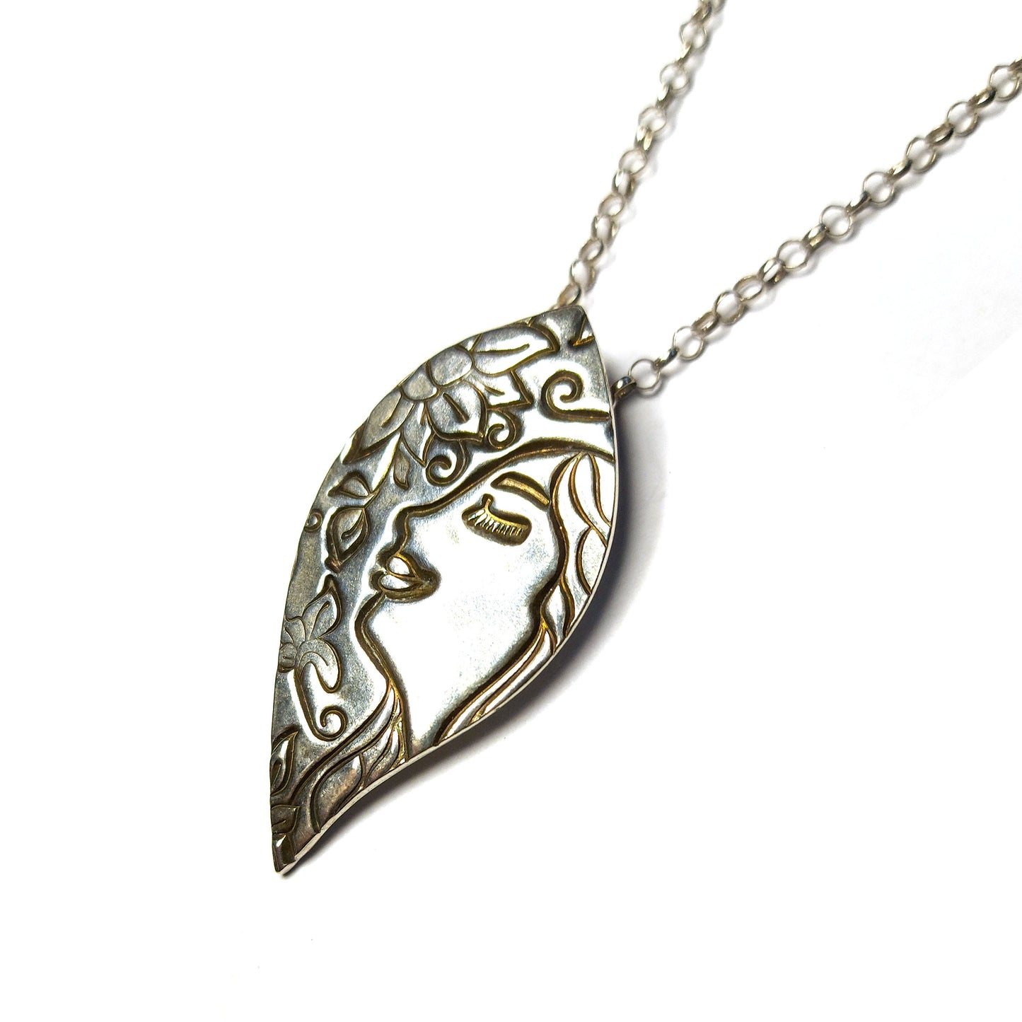 Silver leaf-shaped pendant on silver chain. The pendant features a smiling woman and a flower.