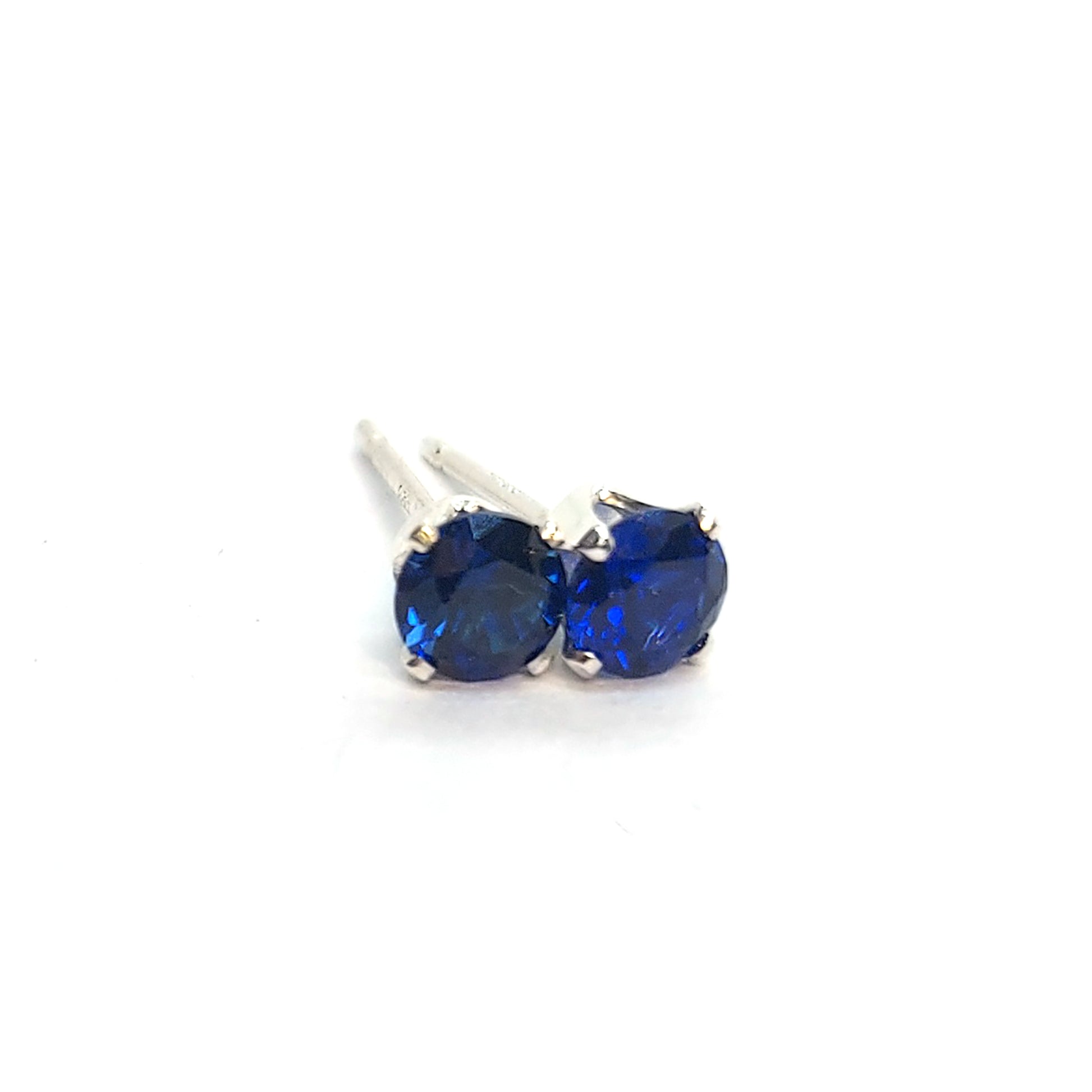 Silver 4 claw stud earrings set with dark blue sapphires. 4mm