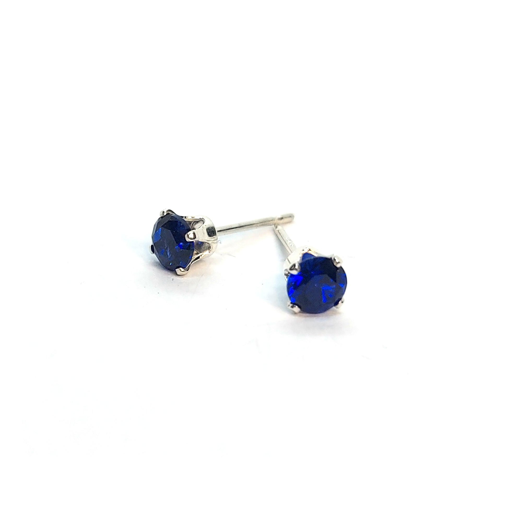 Silver 4 claw stud earrings set with dark blue sapphires. 4mm