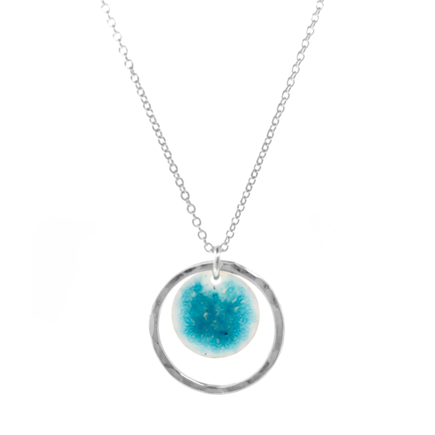 Silver pendant with a central silver disc covered with a turquoise enamel pattern and a surrounding hammered silver circle. On a silver chain.