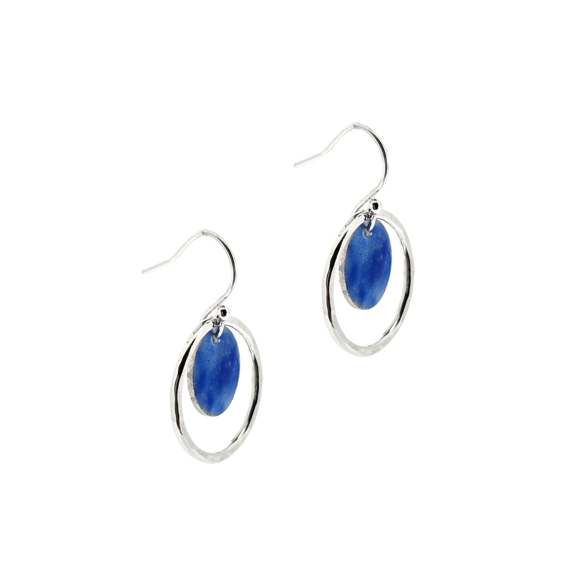 Silver drop earrings with a central disc featuring patterned dark blue enamel surrounded by a silver hammered open circle. 