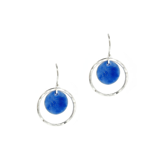 Silver drop earrings with a central disc featuring patterned dark blue enamel surrounded by a silver hammered open circle. 