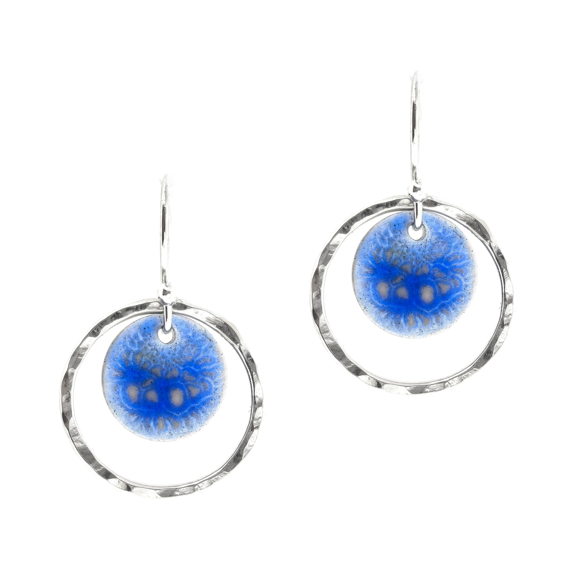 Silver drop earrings with a central disc featuring patterned dark blue enamel surrounded by a silver hammered open circle. 