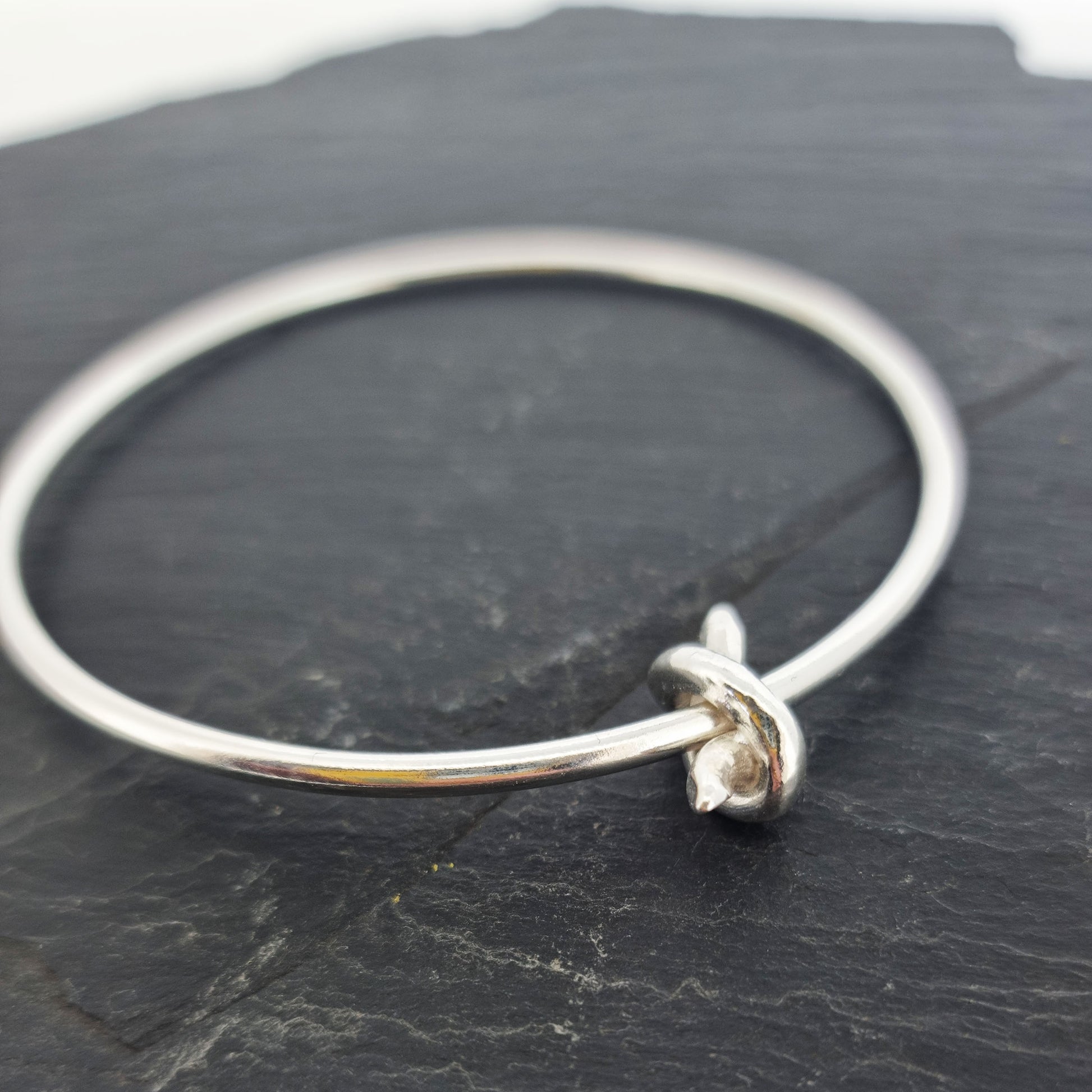 Silver round bangle with spinning knot charm.