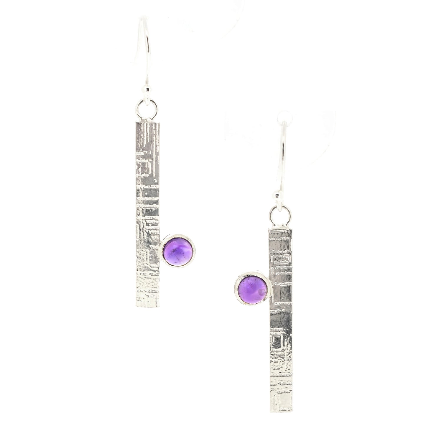 A handmade pair of silver dangle earrings with a textured vertical bar and a round purple amethyst gemstone, shown on a plain white background. Mijoux Jewellery.