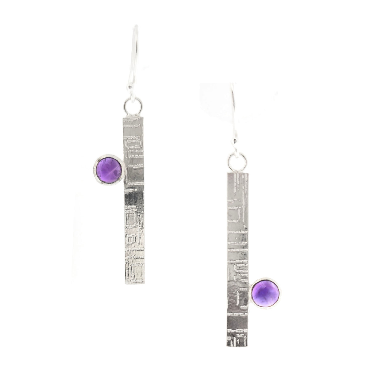 A handmade pair of silver dangle earrings with a textured vertical bar and a round purple amethyst gemstone, shown on a plain white background. Mijoux Jewellery.