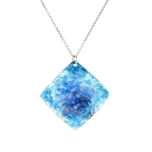 A curved square silver pendant with stars and swirls embossed on it and overlaid with blue and turquoise enamels. Suspended on a silver chain.