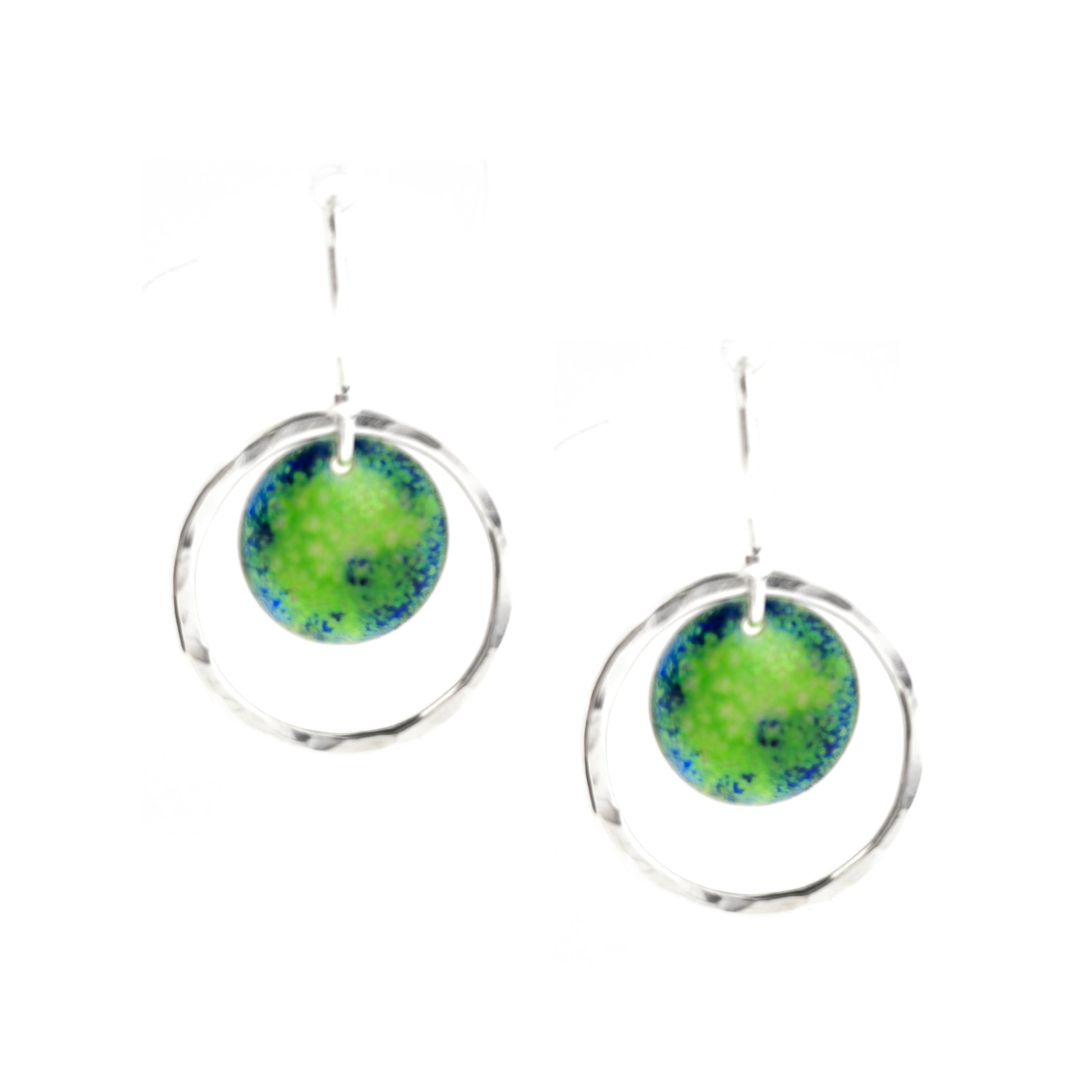 Silver drop earrings consisting of a central disc with a pattern of green and blue enamel surrounded by a silver circle with a hammered finish. On silver ear hooks.