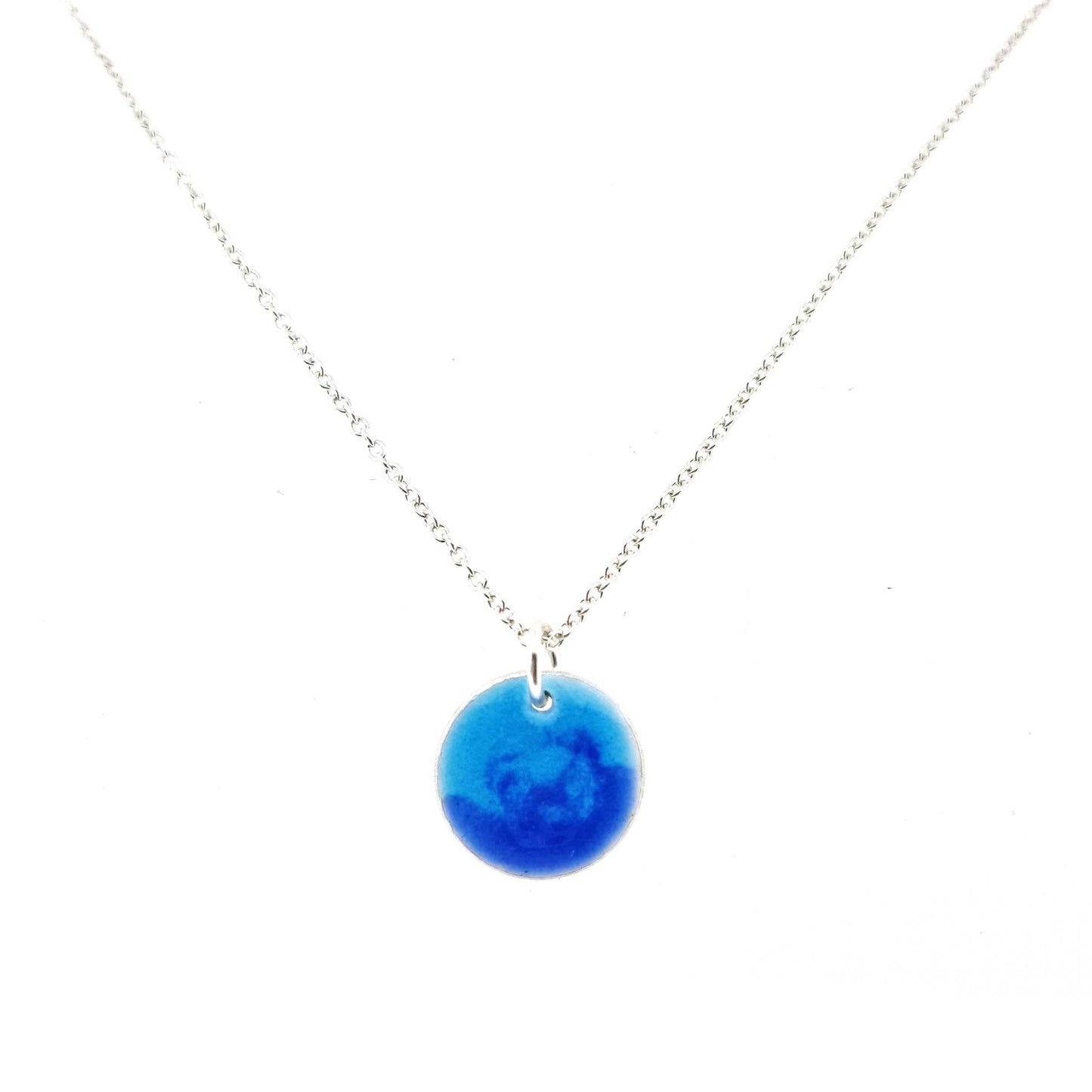 A round silver pendant with a mix of light and dark blue enamel suspended from a silver chain. - small