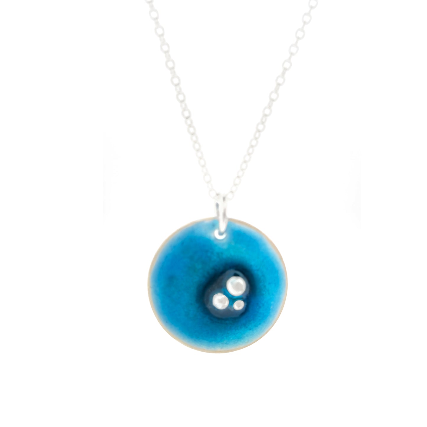 A round domed silver pendant on a silver chain. The pendant has 3 silver balls off-centre and is covered in turquoise blue enamel.