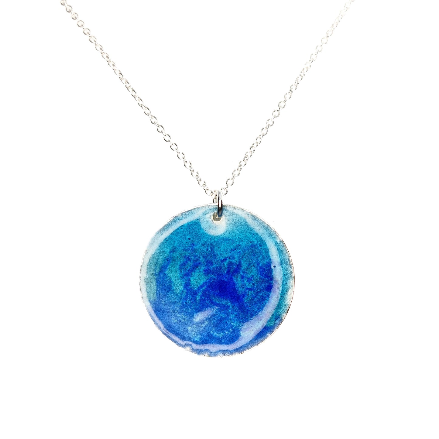 A round silver pendant with a mix of light and dark blue enamel suspended from a silver chain. - large