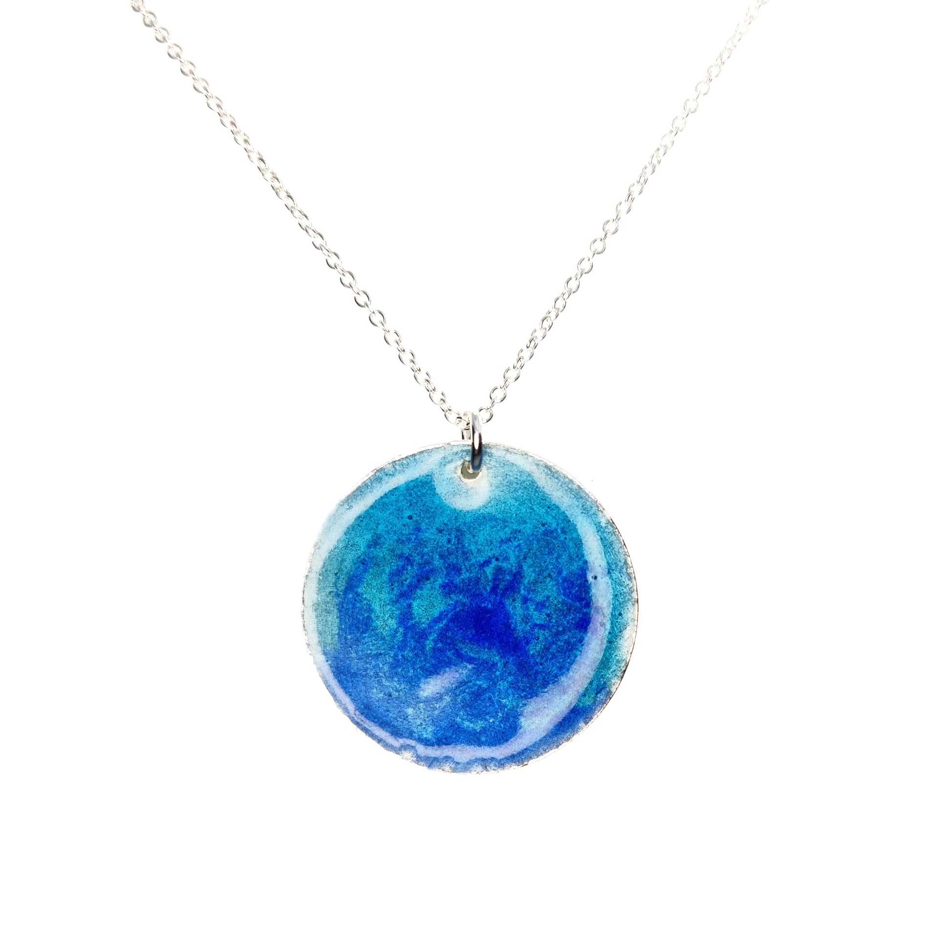 A round silver pendant with a mix of light and dark blue enamel suspended from a silver chain. - large