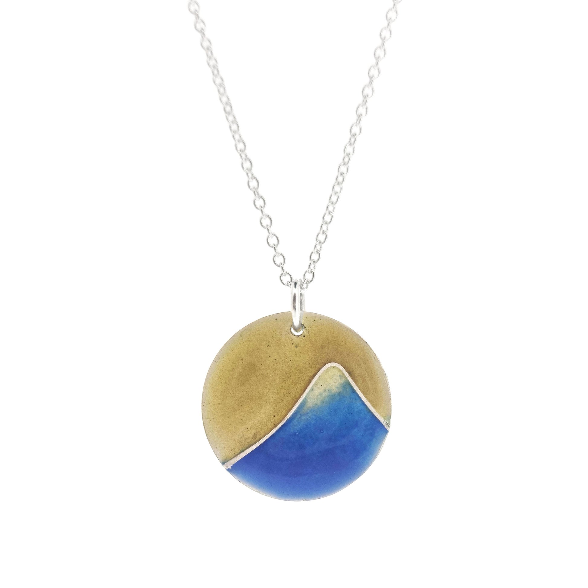 A round silver pendant with a graduated blue enamel mountain and a yellow enamel background. On a silver chain.