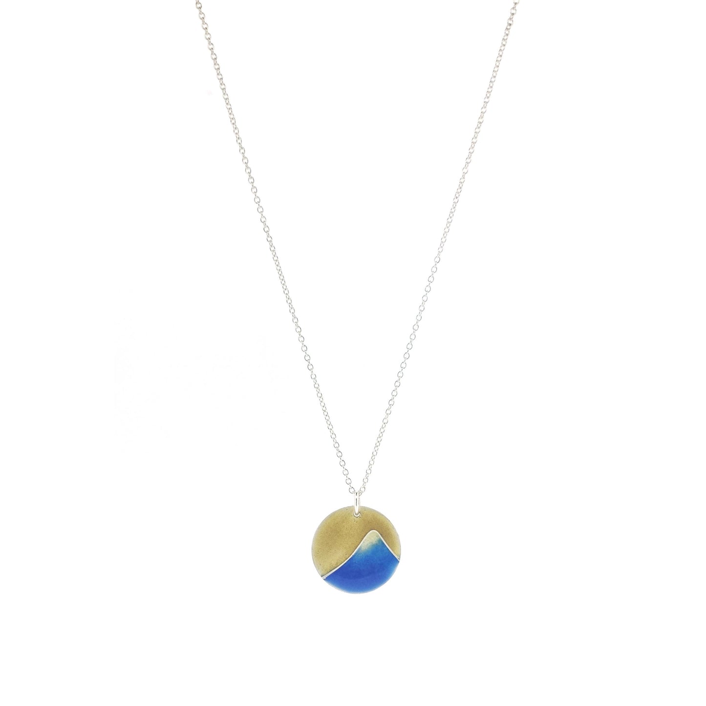 A round silver pendant with a graduated blue enamel mountain and a yellow enamel background. On a silver chain.