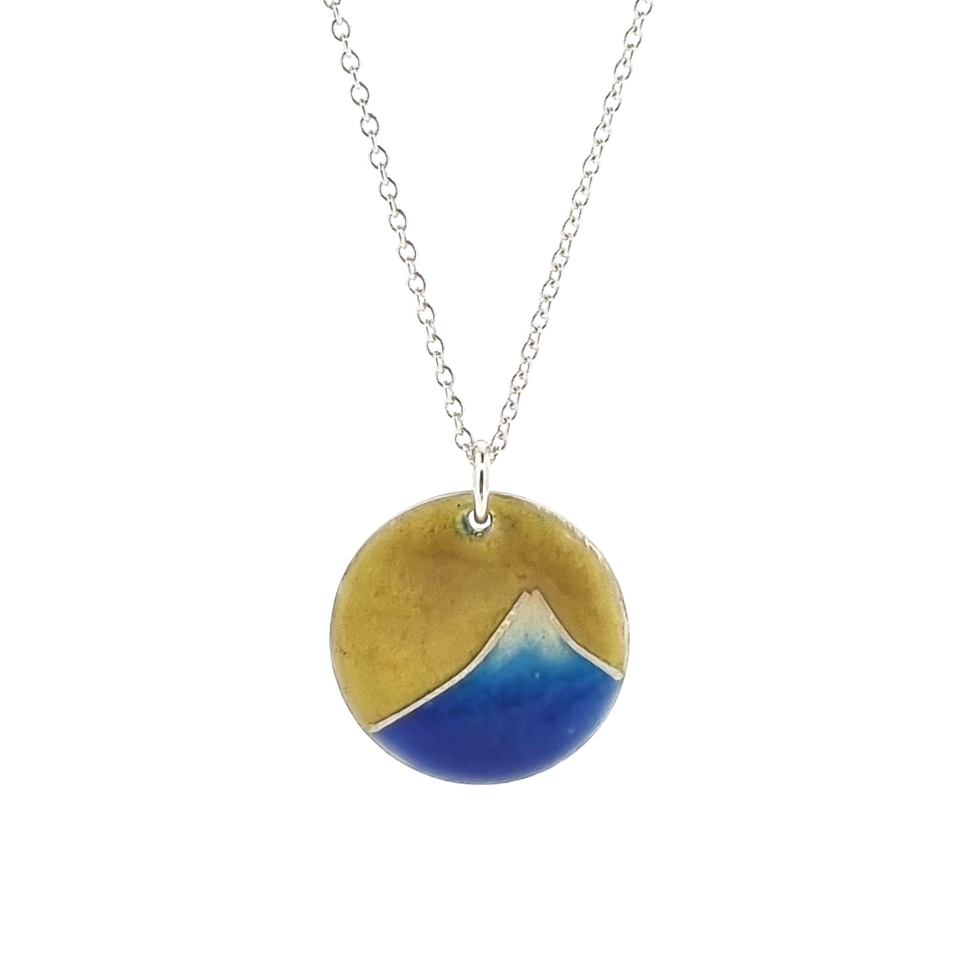 A round silver pendant with a graduated blue enamel mountain and a yellow enamel background. On a silver chain.