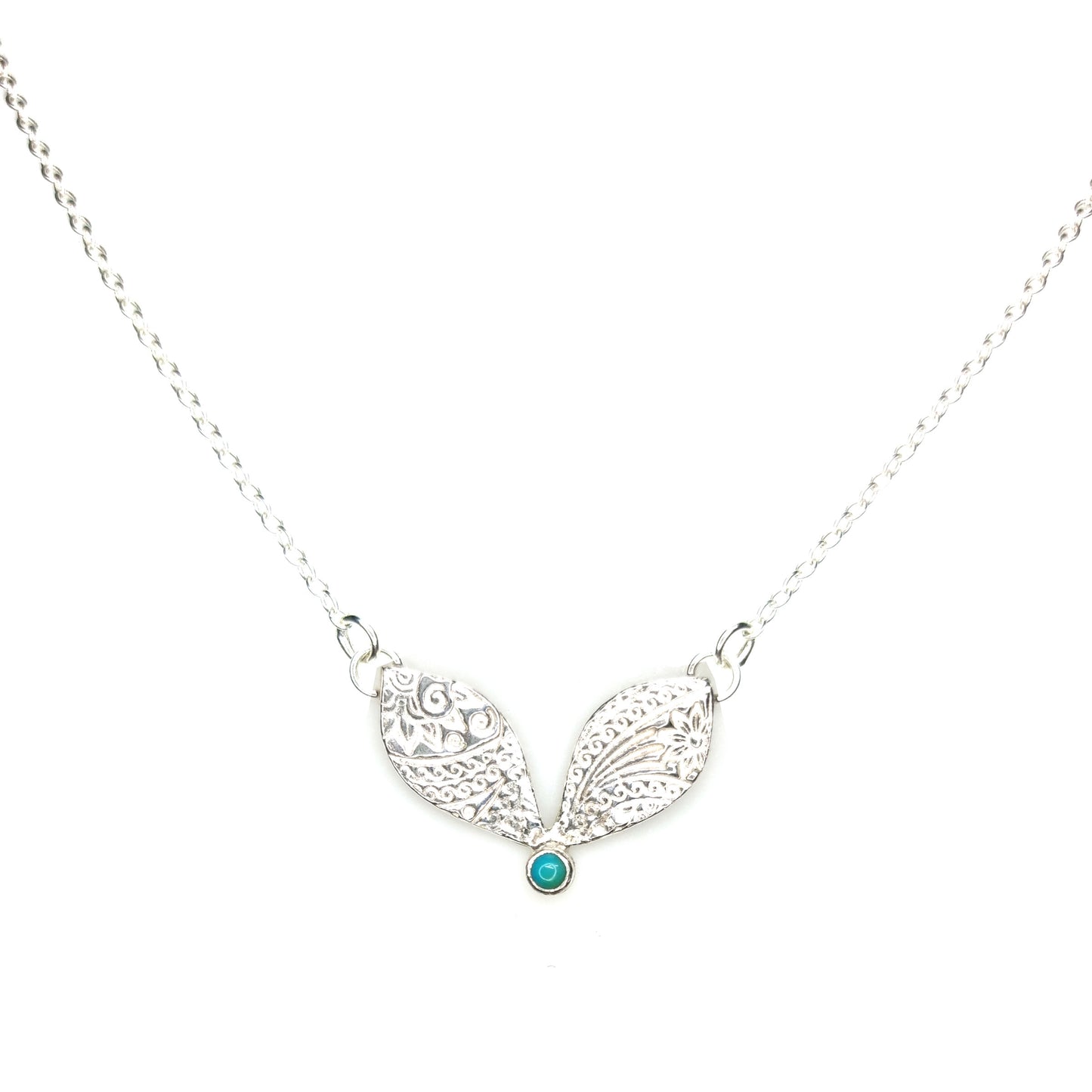 A silver necklace with a focal patterned element set with a turquoise gemstone.