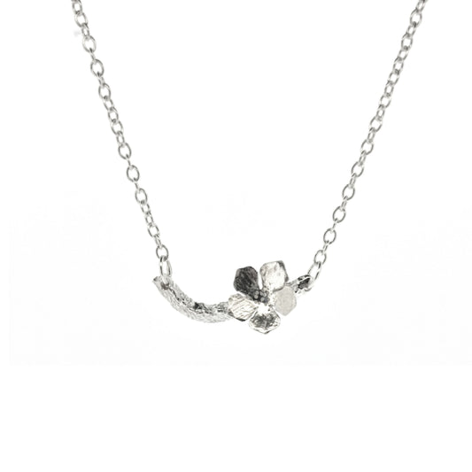 Silver necklace with small branch and a single 5 petal flower on it.
