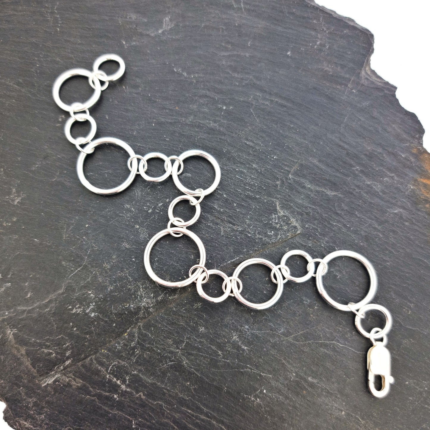 Silver chain link bracelet with circle links of different sizes.