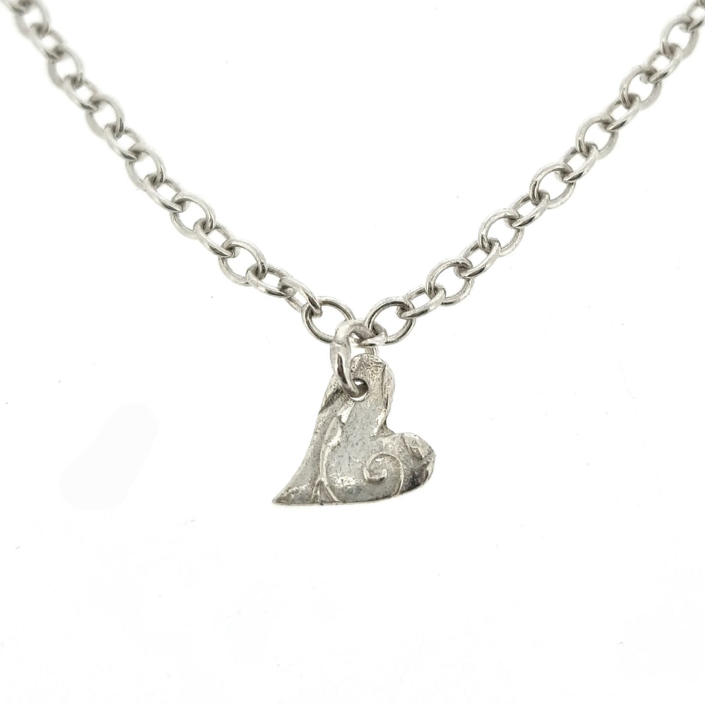 Sterling silver adjustable chain bracelet with small asymmetrical heart charm.