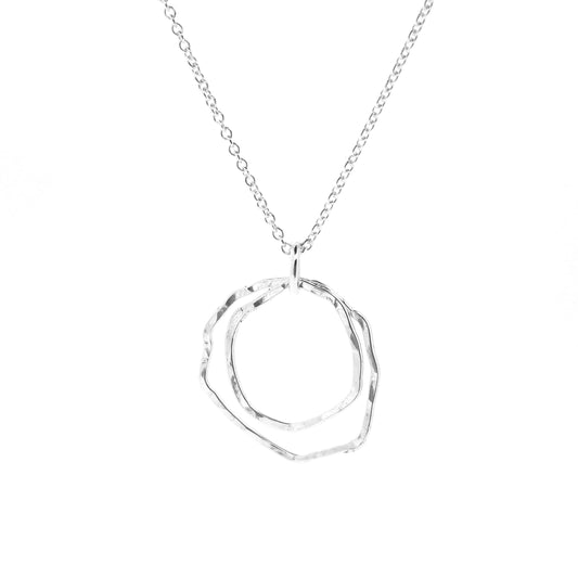 A silver pendant consisting of two organic rustic style open circles of different sizes suspended from a silver chain.