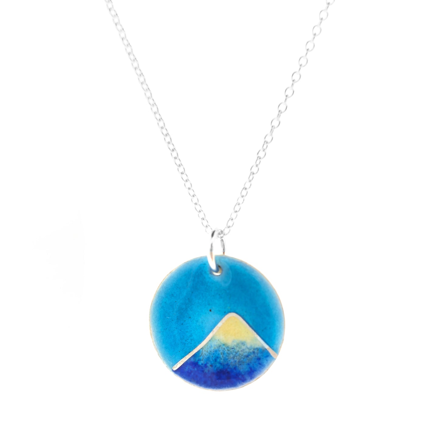 Silver and enamel round pendant featuring a dark blue and white mountain with a turquoise blue sky. On a silver chain.