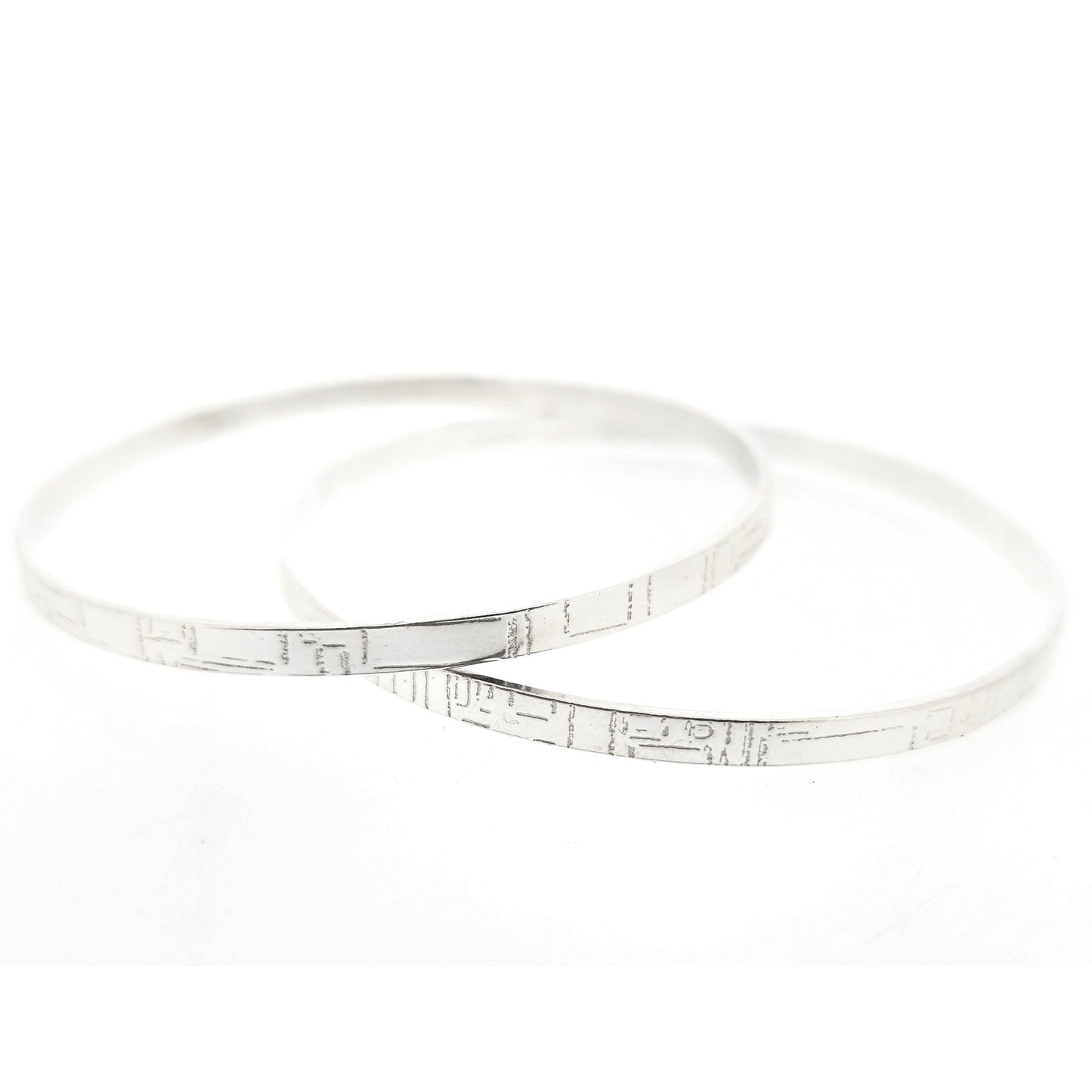 Two flat silver bangles with a square and line pattern. Mijoux Jewellery.