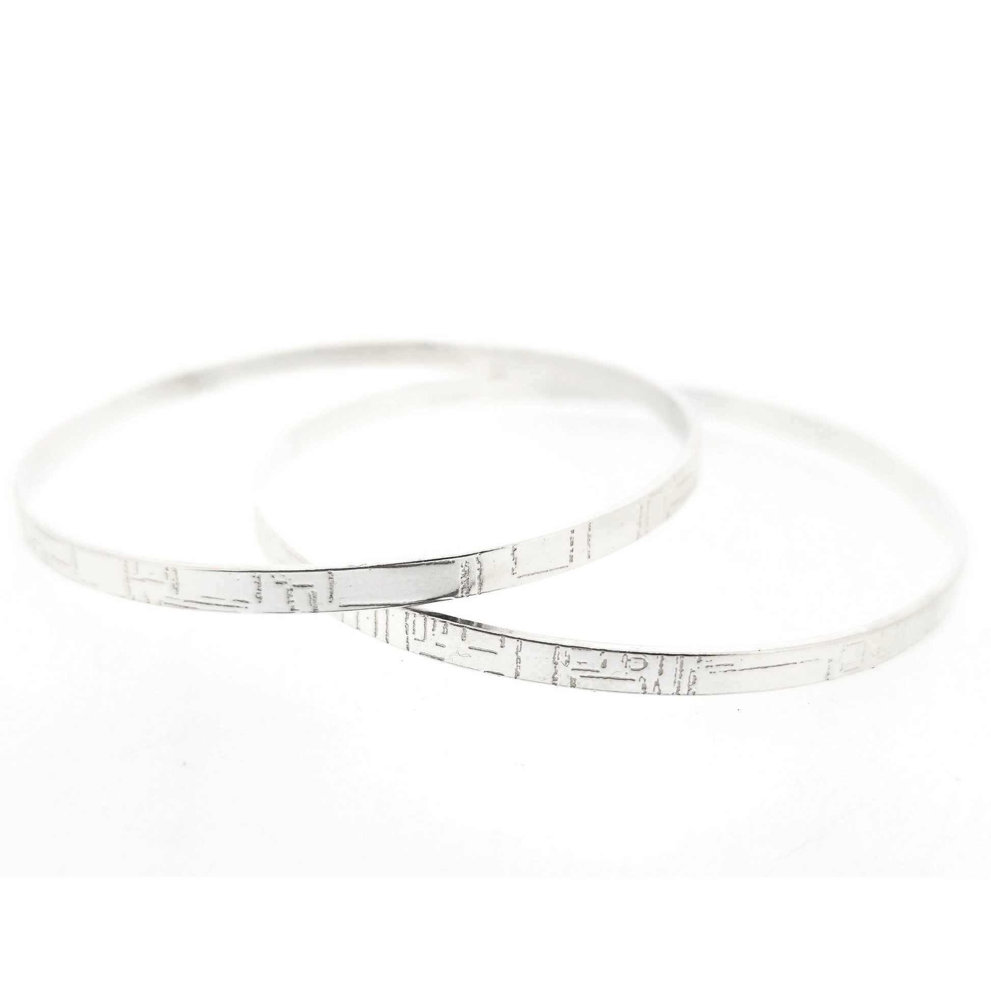Two flat silver bangles with a square and line pattern. Mijoux Jewellery.