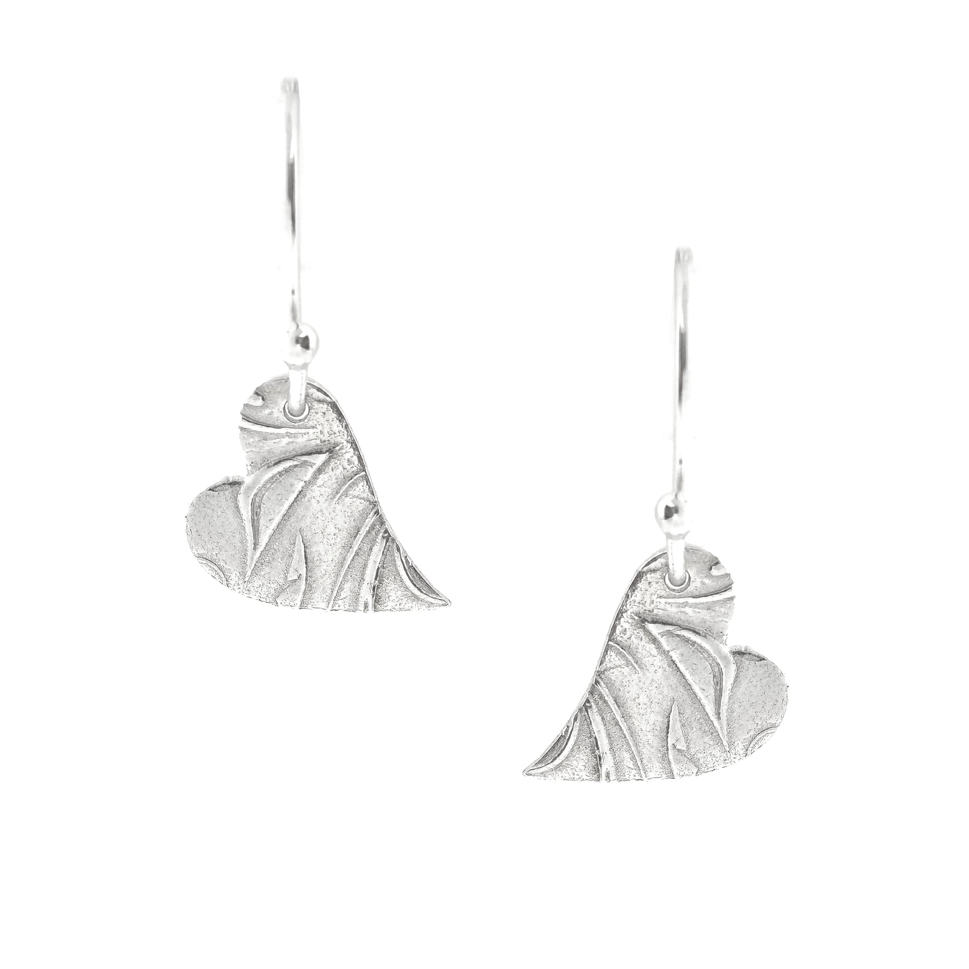 Silver heart drop earrings featuring an asymmetrical heart with a leaf and vine pattern suspended from silver ear hooks.