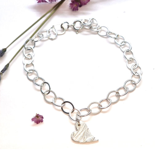 Silver large link chain bracelet with asymmetrical patterned heart charm.