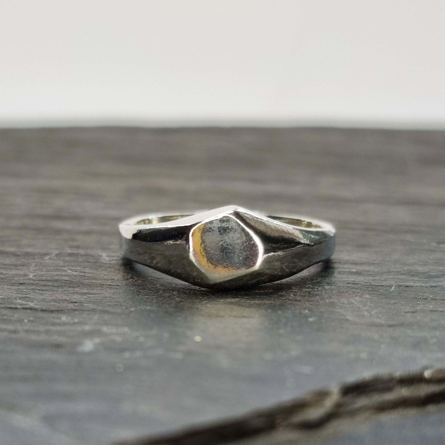 A silver geometric signet ring with flat head.