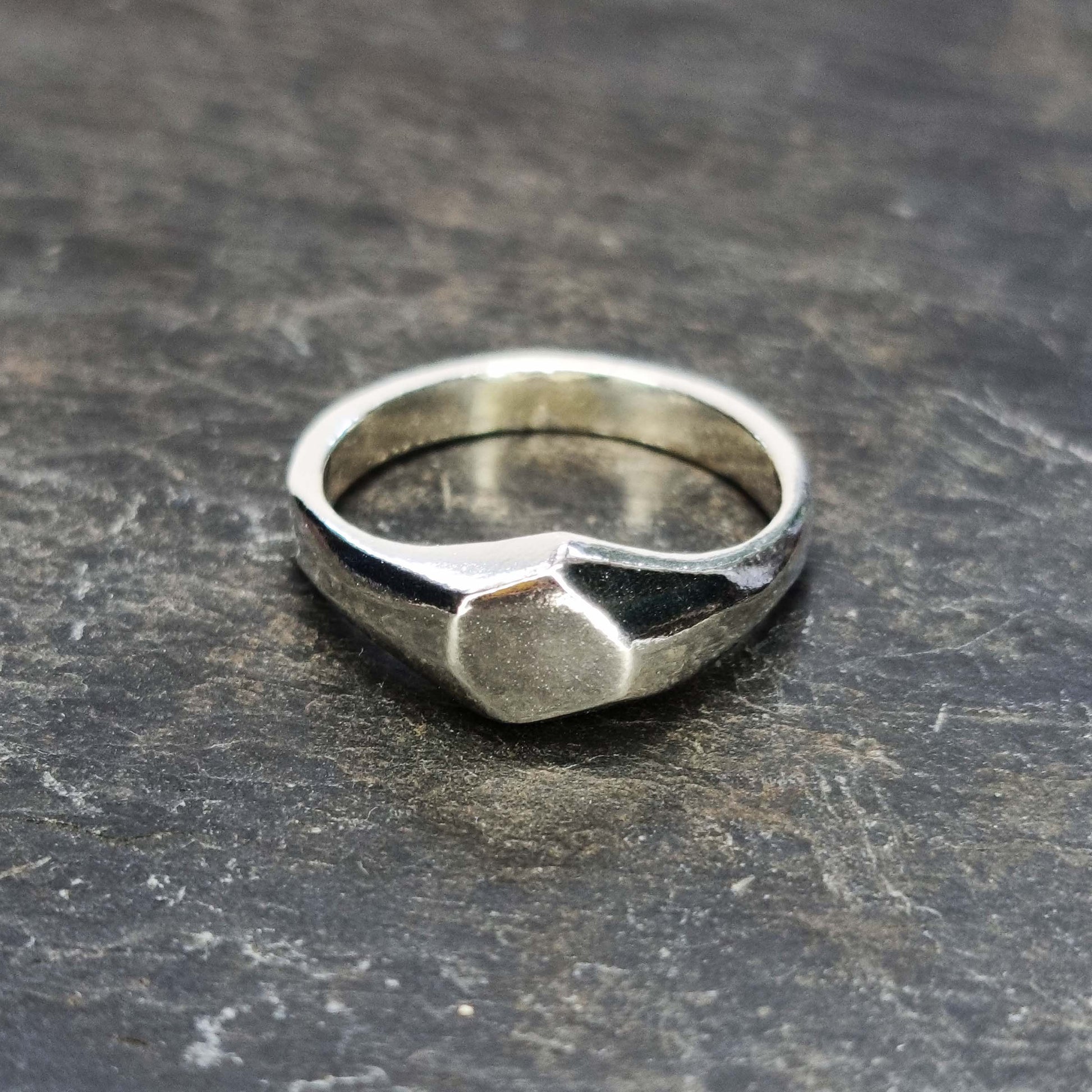 A silver geometric signet ring with flat head.