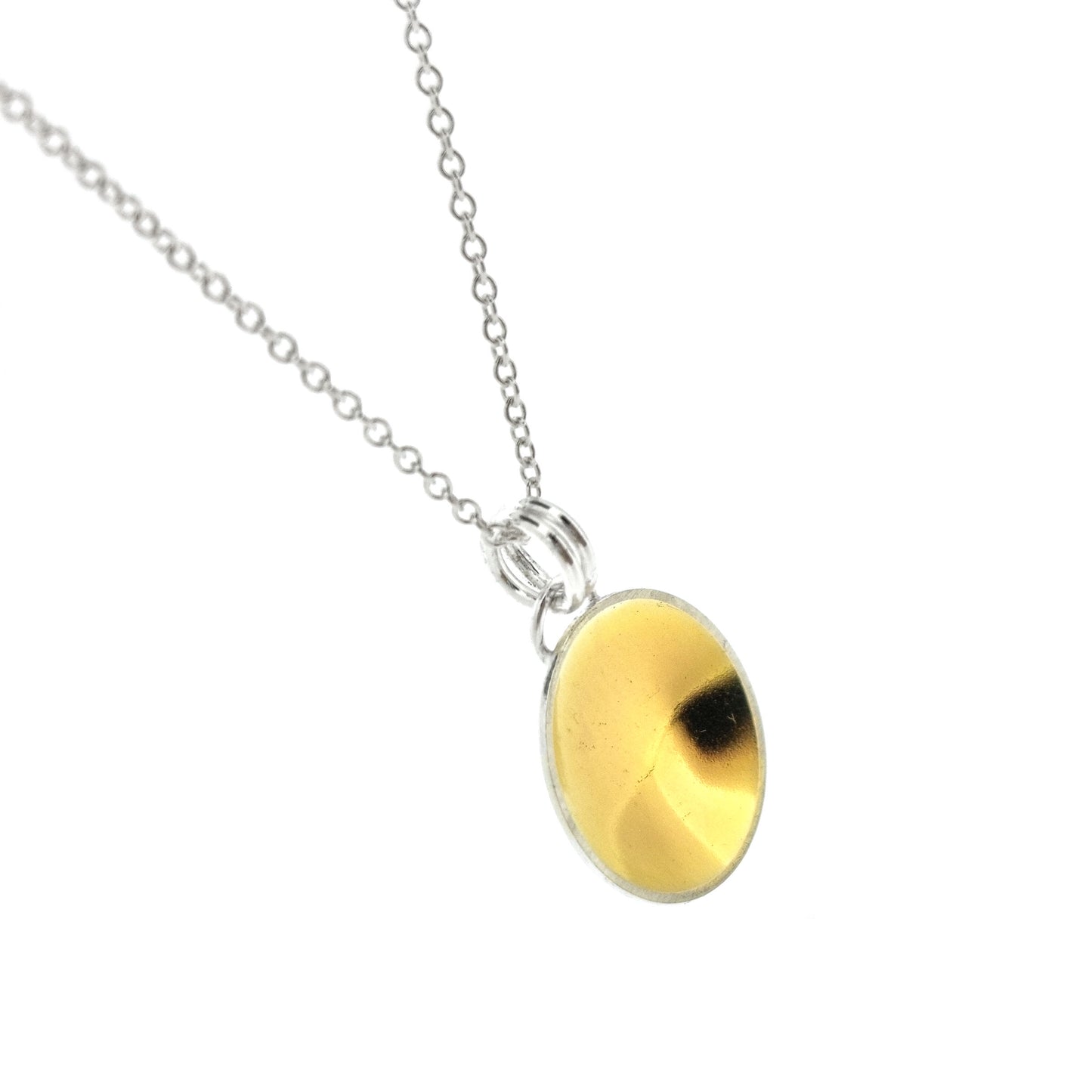 A silver round domed pendant with a gold center and double bail suspended from a silver chain. Side view.