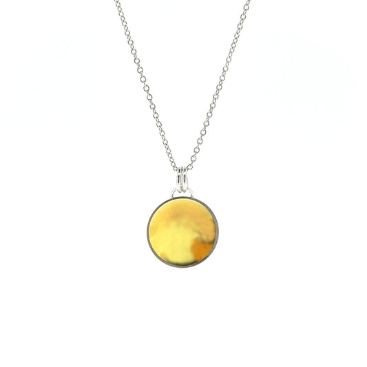 A silver round domed pendant with a gold center and double bail suspended from a silver chain.