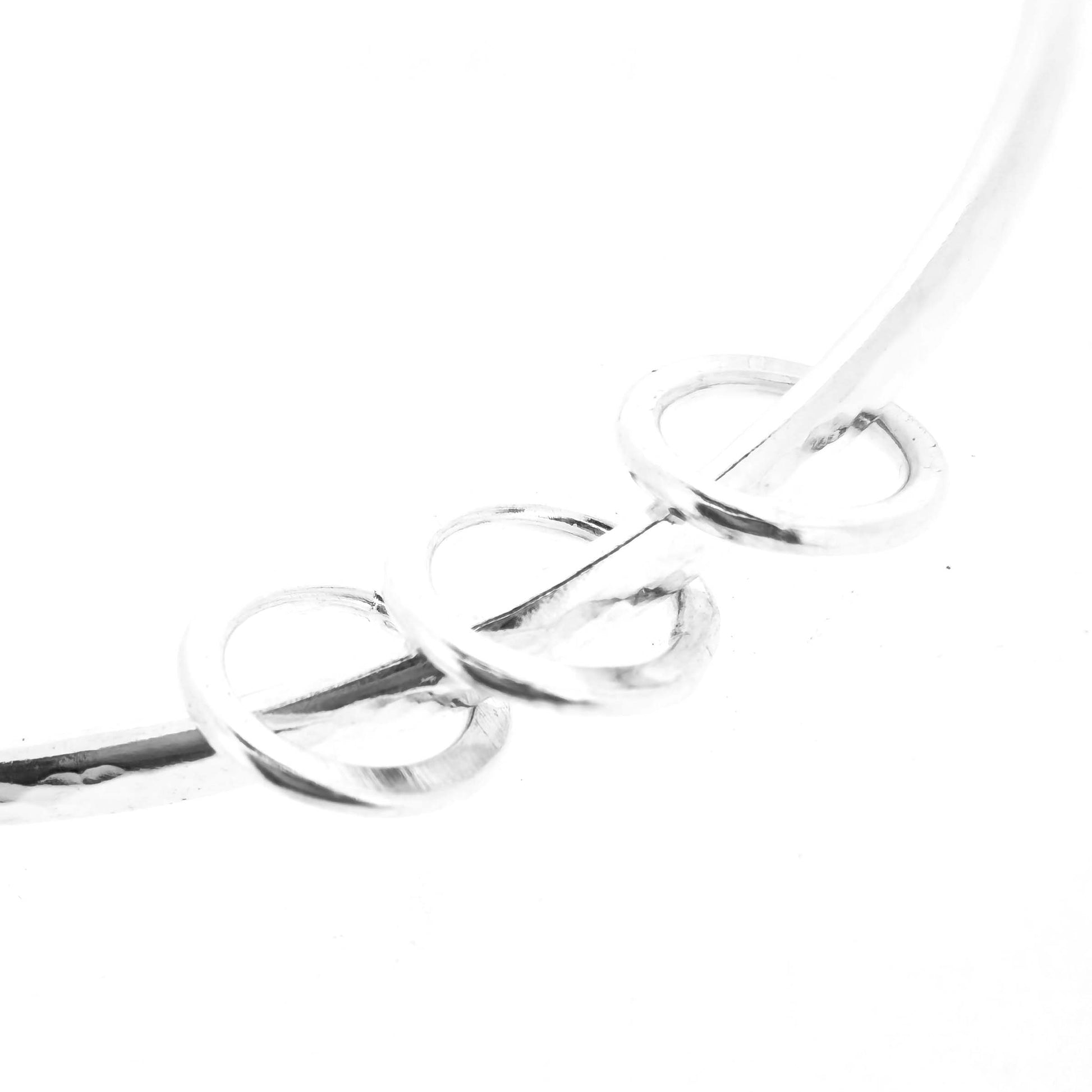 Section of silver textured bangle with 3 circle beads on a white background