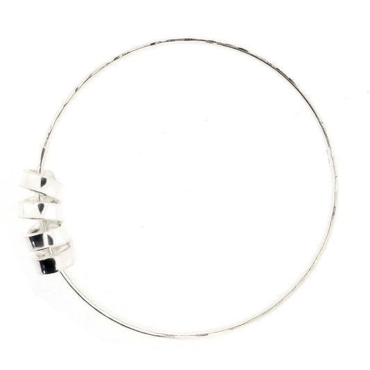 Silver bangle with a hammered finish and a wide spiral bead on a white background.
