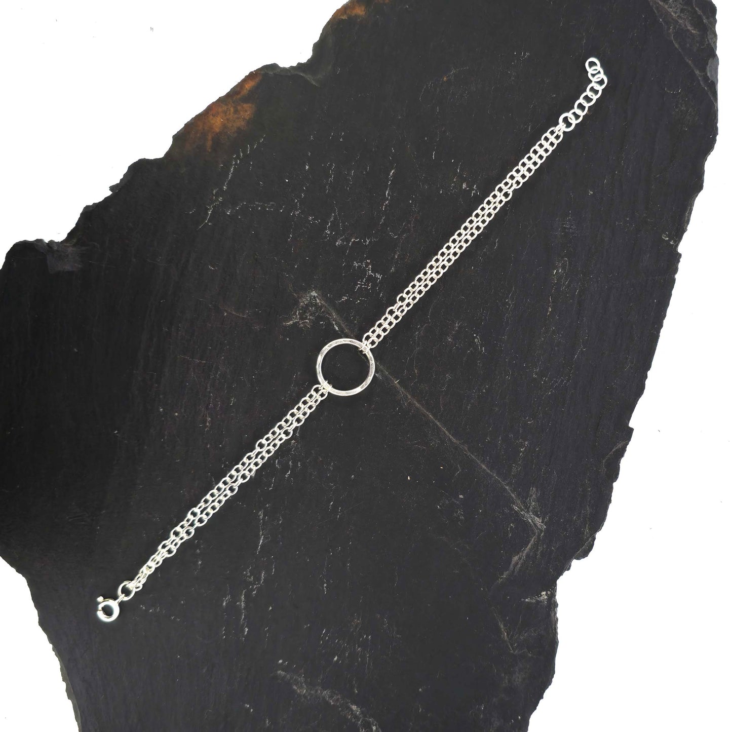 Silver double chain bracelet with a central hammered circle on a slate background