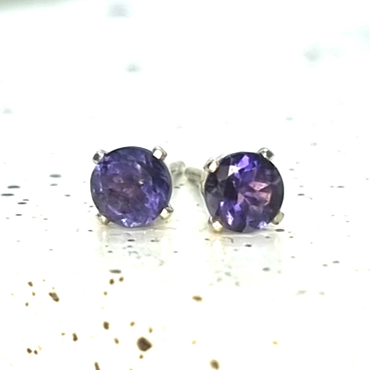 Pair of purple gemstone stud earrings on a white background