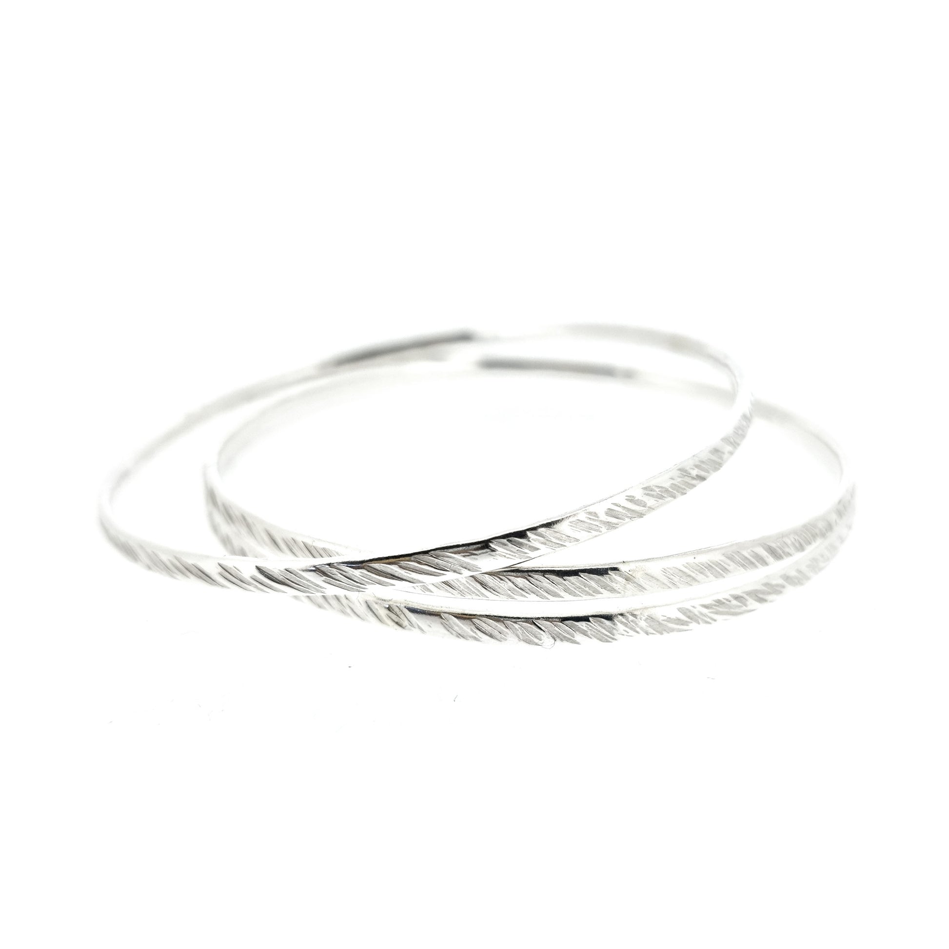 A set of 3 silver round bangles with a diagonal rustic lined texture.