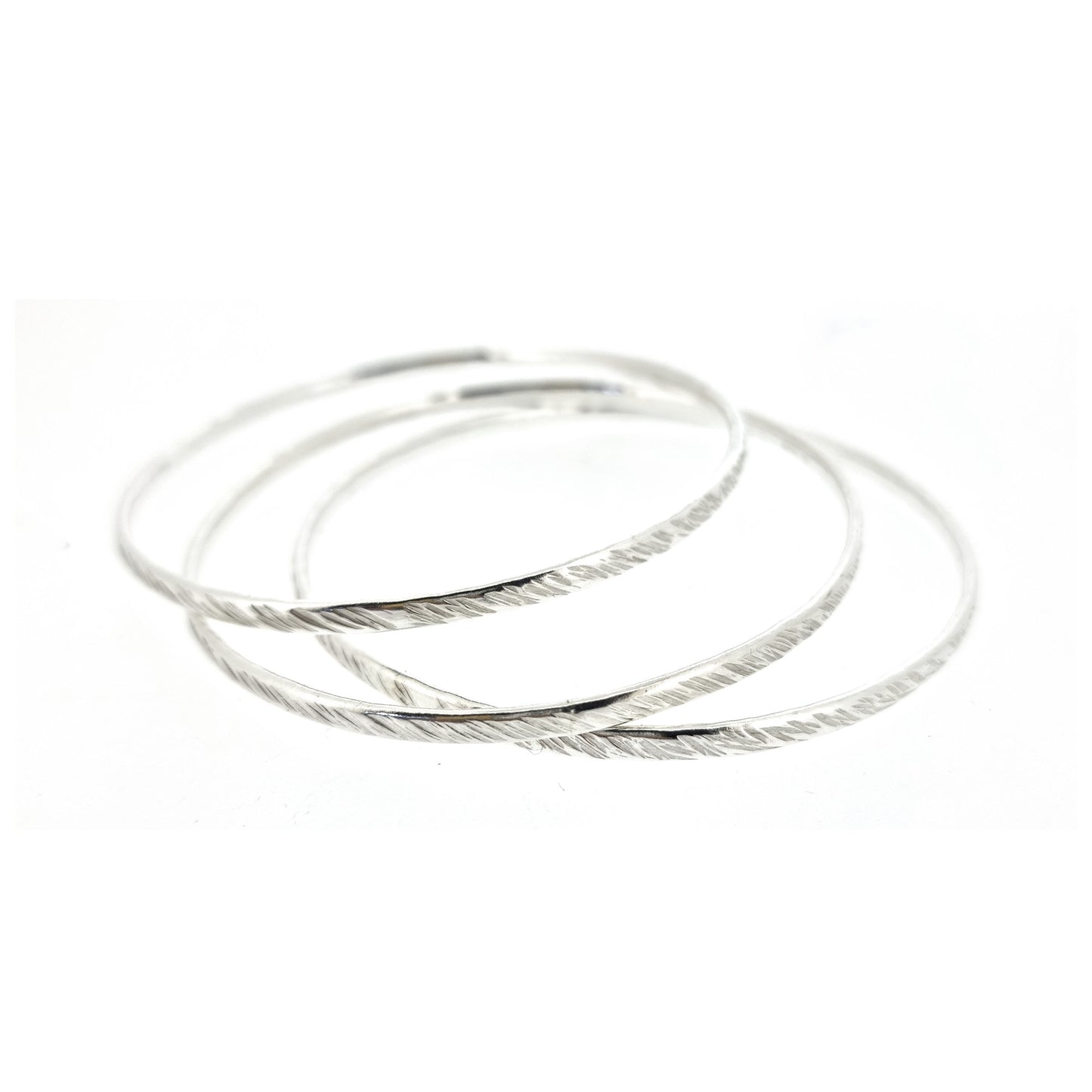 A set of 3 silver round bangles with a diagonal rustic lined texture.