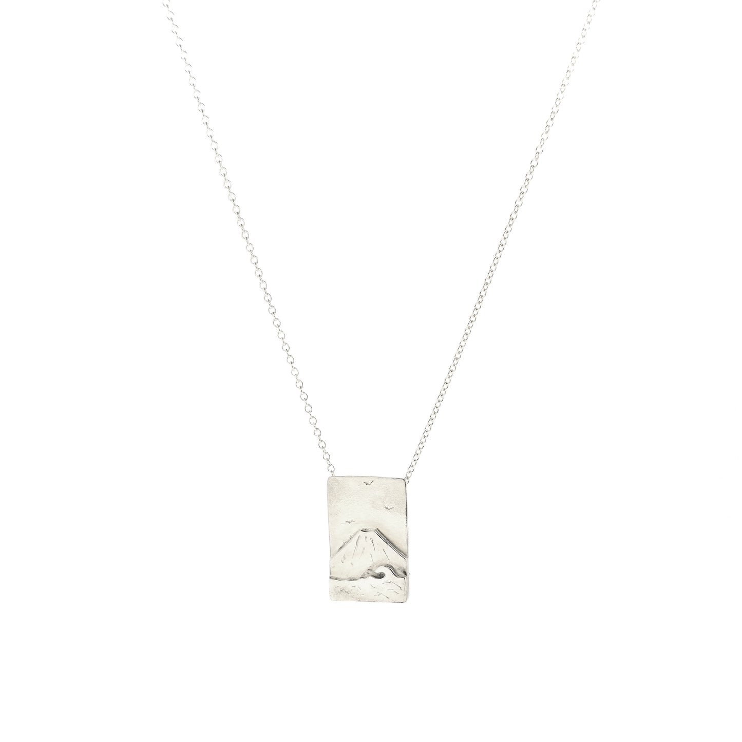 A rectangular silver pendant with a mountain scene featuring Mount Fuji behind a sea with a wave and birds in the sky. On a silver chain with invisible bail. Mijoux Creations.