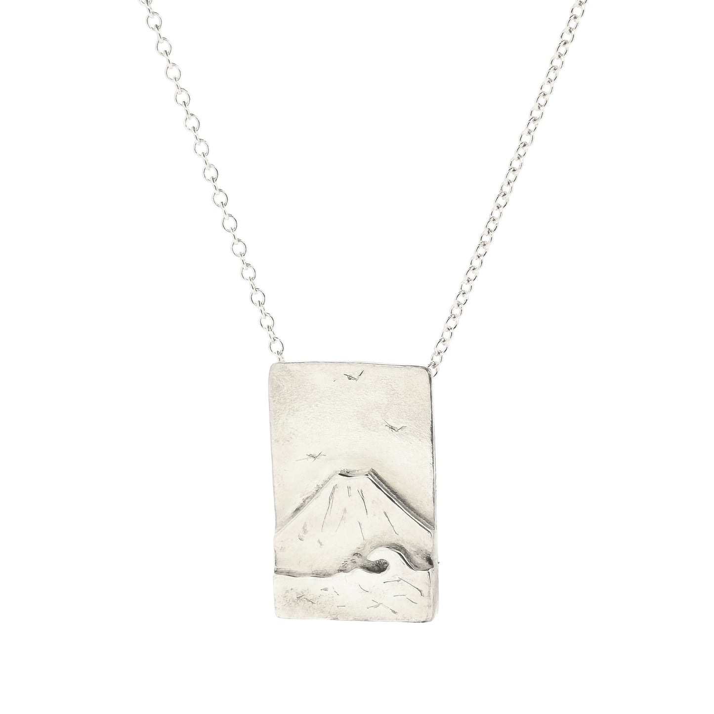 A rectangular silver pendant with a mountain scene featuring Mount Fuji behind a sea with a wave and birds in the sky. On a silver chain with invisible bail.