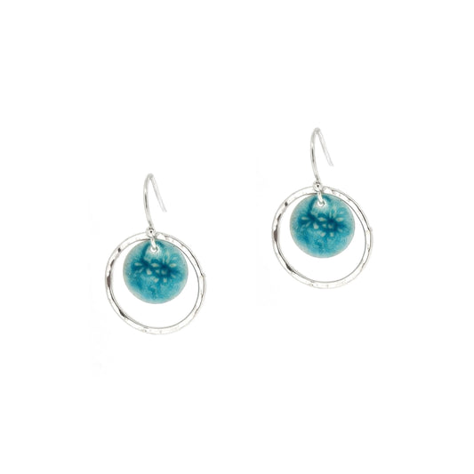 Silver drop earrings with a central silver disc covered with a turquoise enamel pattern and a surrounding hammered silver circle.