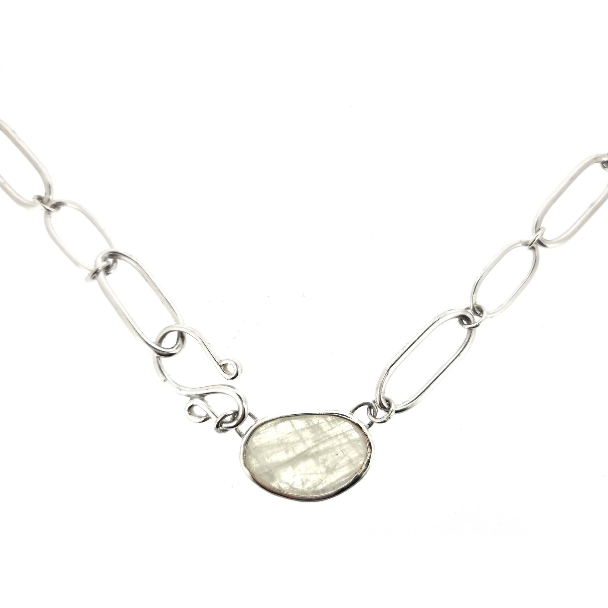 A silver chain necklace with open oblong links of different sizes, an s-clasp and a moonstone slice in a bezel setting.