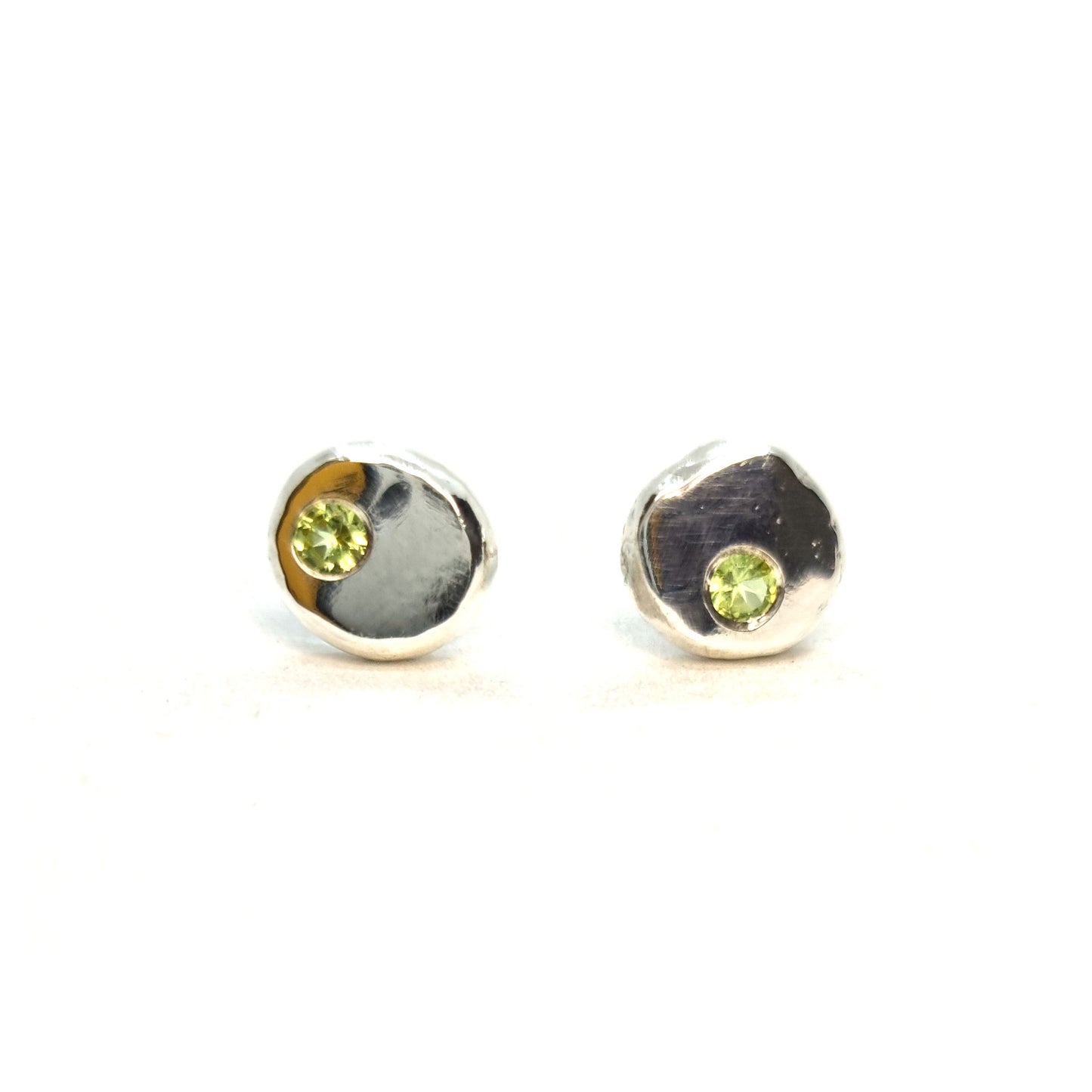 Silver round flat 'pebble' stud earrings set with pale green peridot gemstones.