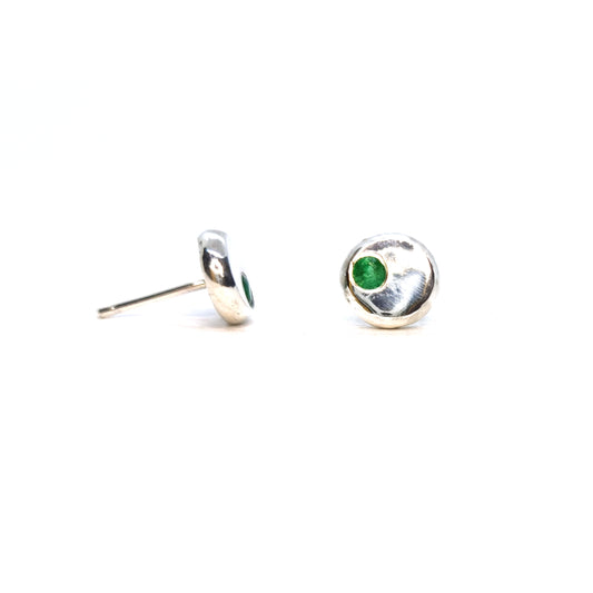 Round silver pebble stud earrings with green emerald gemstones set off-centre.