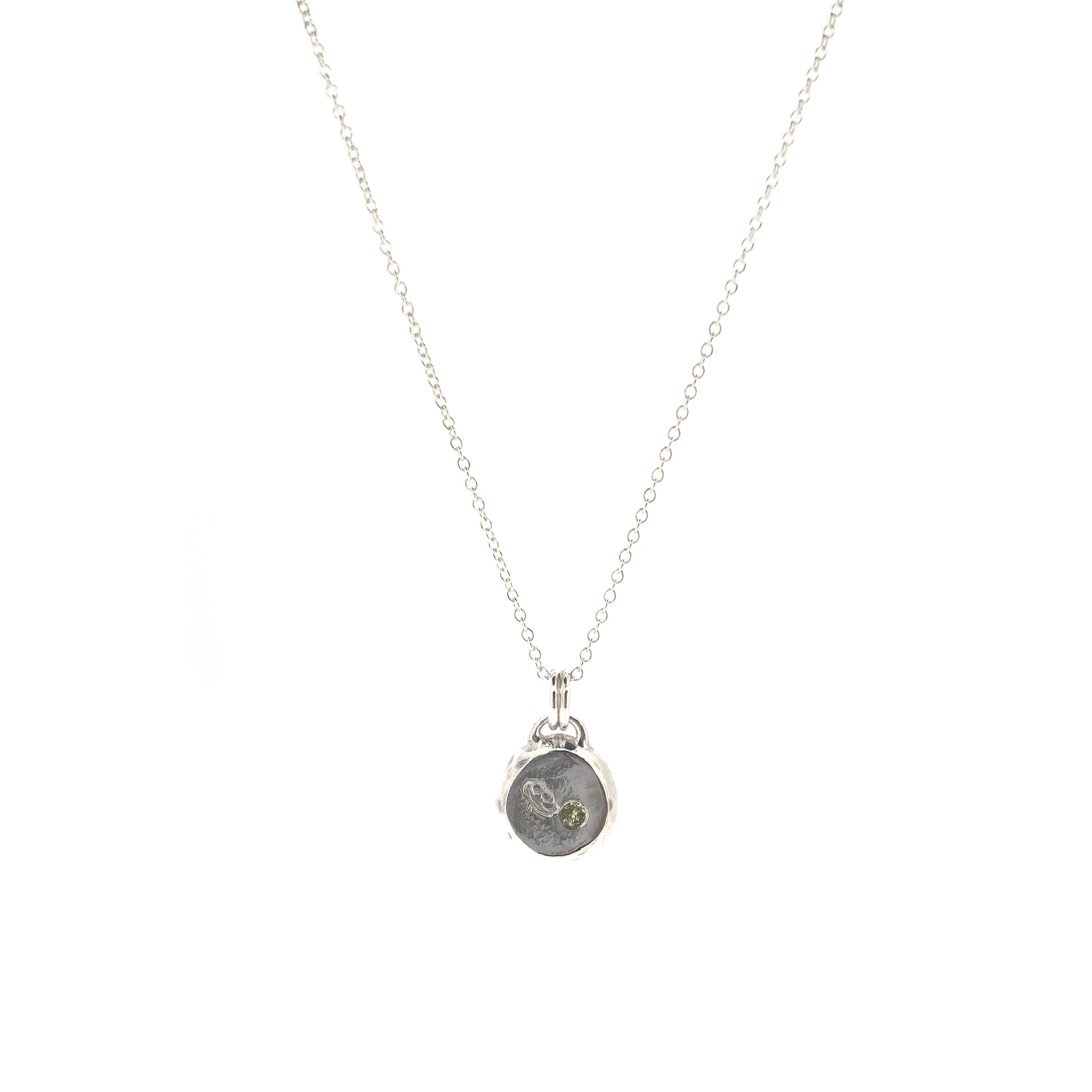 Silver round flat 'pebble' birthstone pendant with a poppy engraved on it and a pale green peridot gemstone on a silver chain. - August