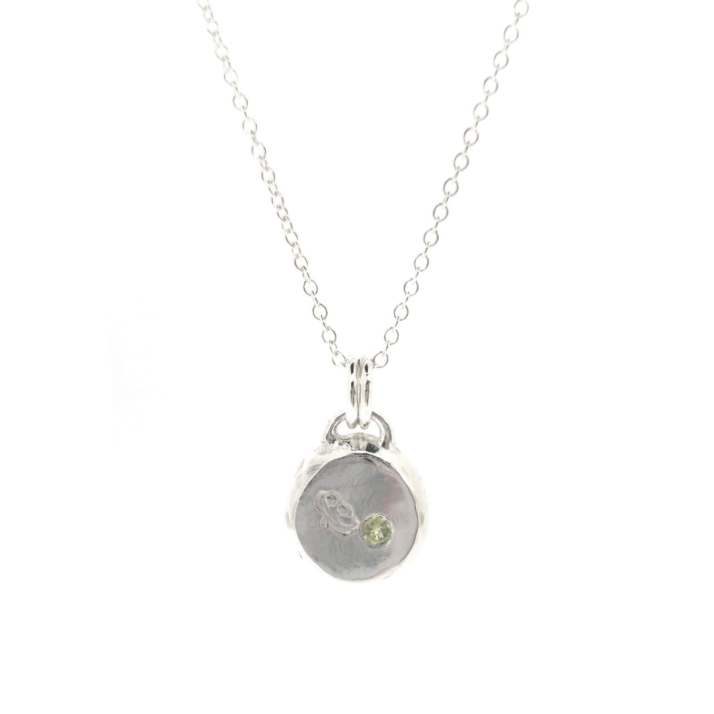 Silver round flat 'pebble' birthstone pendant with a poppy engraved on it and a pale green peridot gemstone on a silver chain. - August