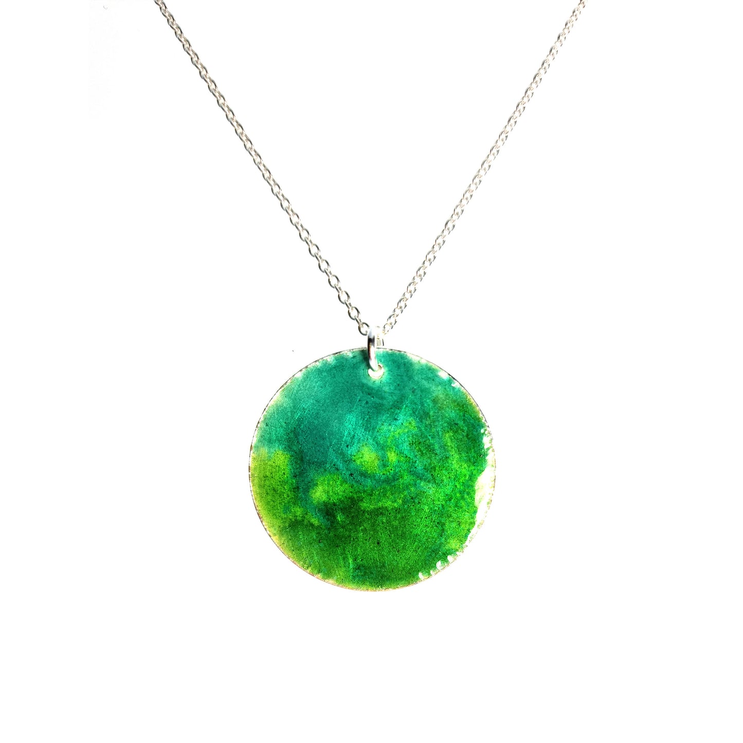 A round silver pendant with a mix of green enamels. on a silver chain.